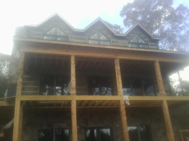 Dormers and porch framing on a large log home under construction — Roof Coating work by our crew in Brownsville